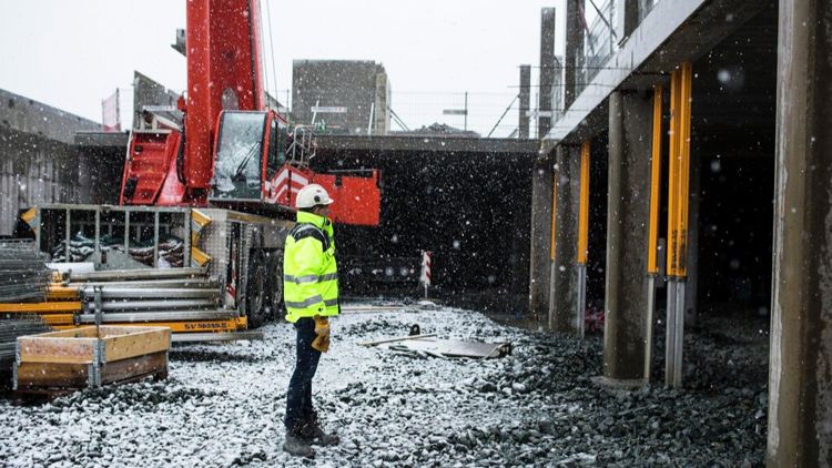 person som står på en snødekt byggeplass