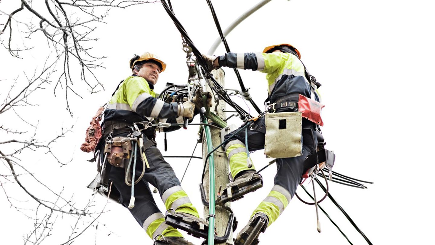 To arbeidere som jobber oppe i en høyspentmast 