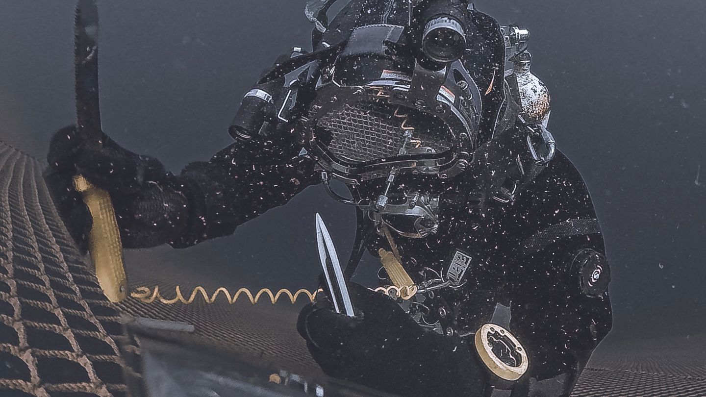 en dykker jobber under vann i en lukket merde 